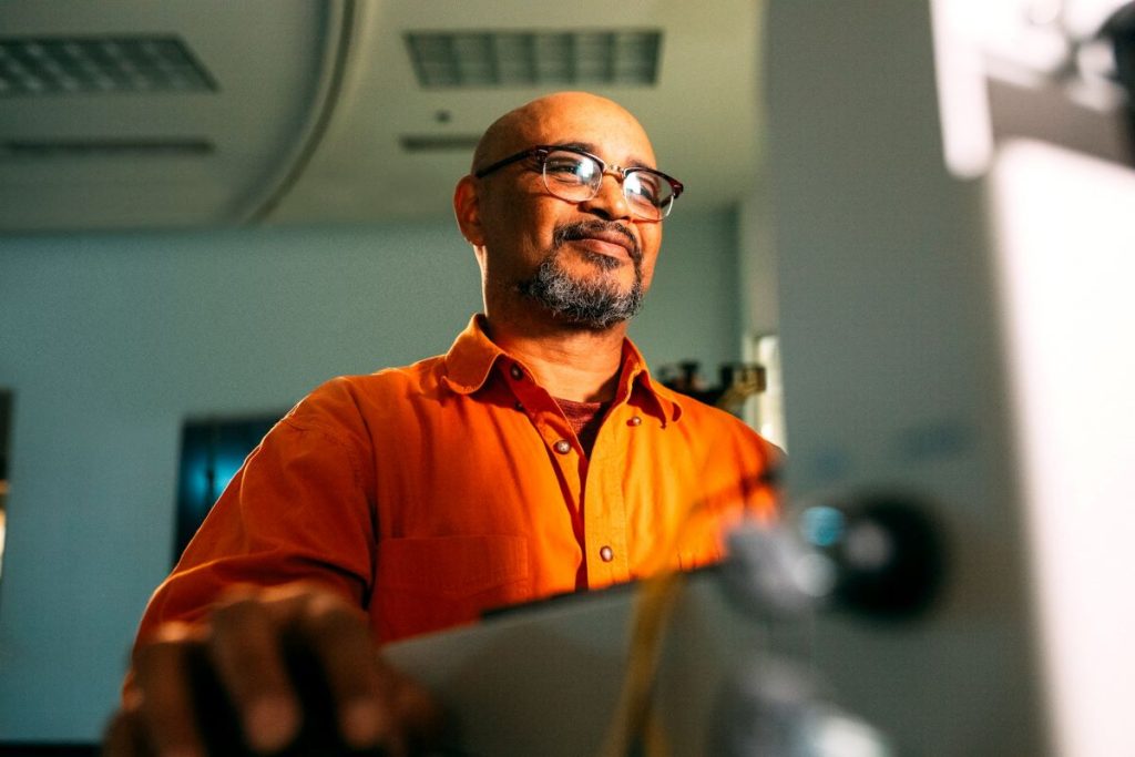 man smiling thinking of the value of labour day while working on the computer