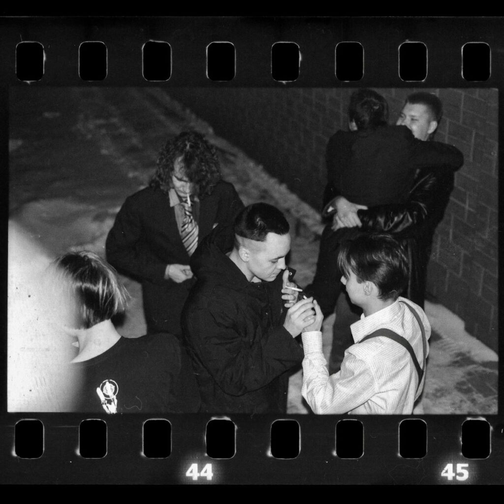 group of men wearing suits smoking and hugging in an alley shows that we need to stop romanticizing crime