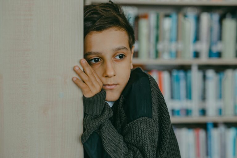 A lonely child looking out somewhere away from a shelf of books.