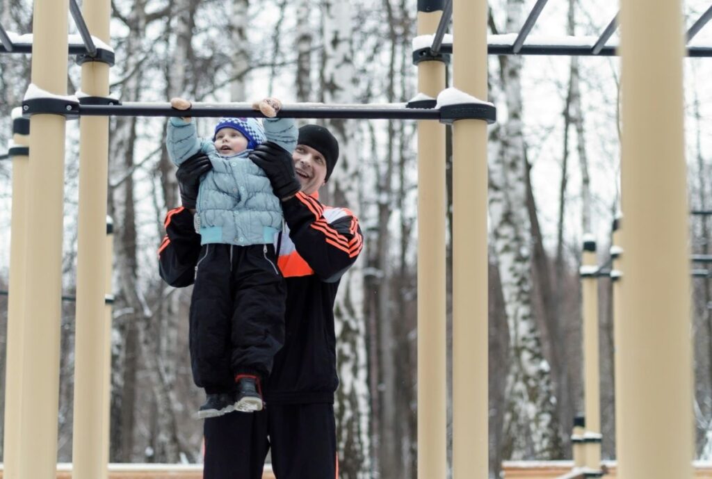 image of father helping his child do some pull ups as he knows why kids need exercise