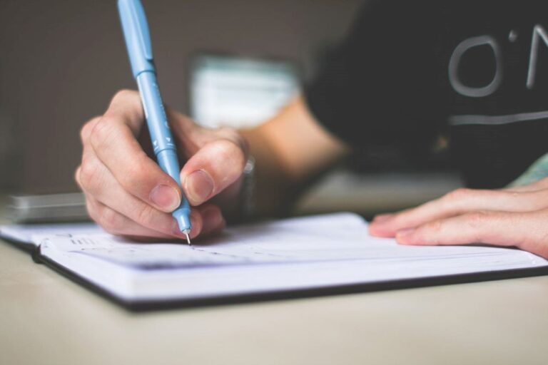 image of a person writing on a notebook as they apply the tips on writing a limerick poem they have learned