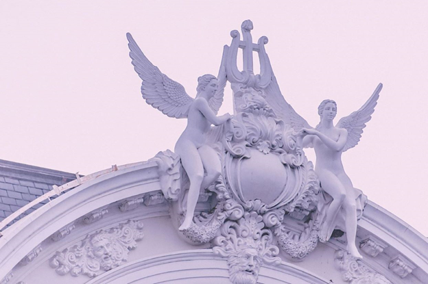 Stone statues of two angels perched atop a building.