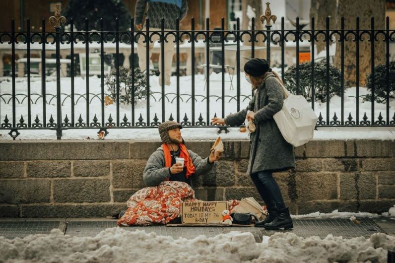 A woman helping a homeless man.