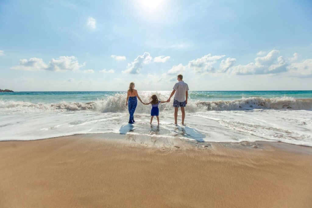 image of a family standing on the shore as a wave approaches them to display what it means to take care of children