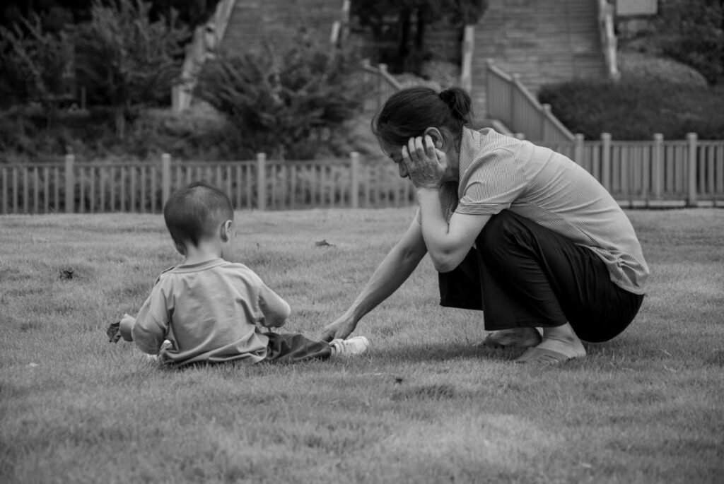 image of a mother playing with her child on a field talking about growing up as a blind child