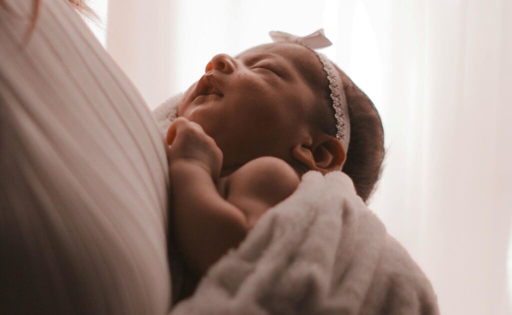 A baby sleeping against their mother's chest.