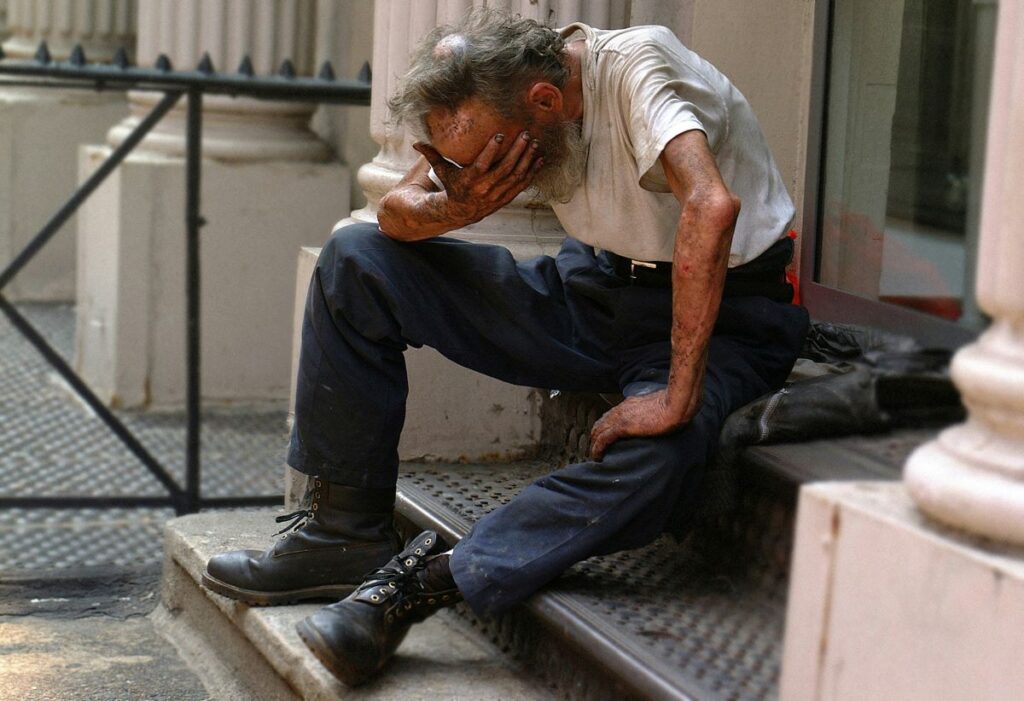 image of old man sitting down on steps with his hand covering his face worried about the problem of homelessness among veterans