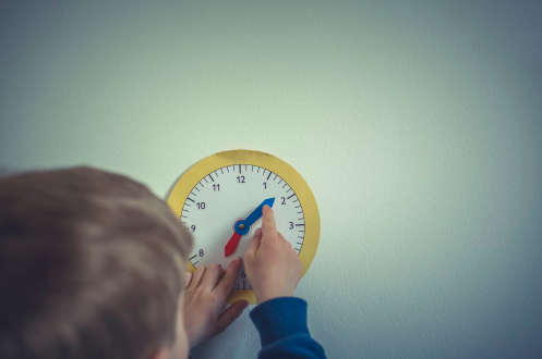 a boy learning to read time through a dummy clock that allows him to set time in an active learning set-up