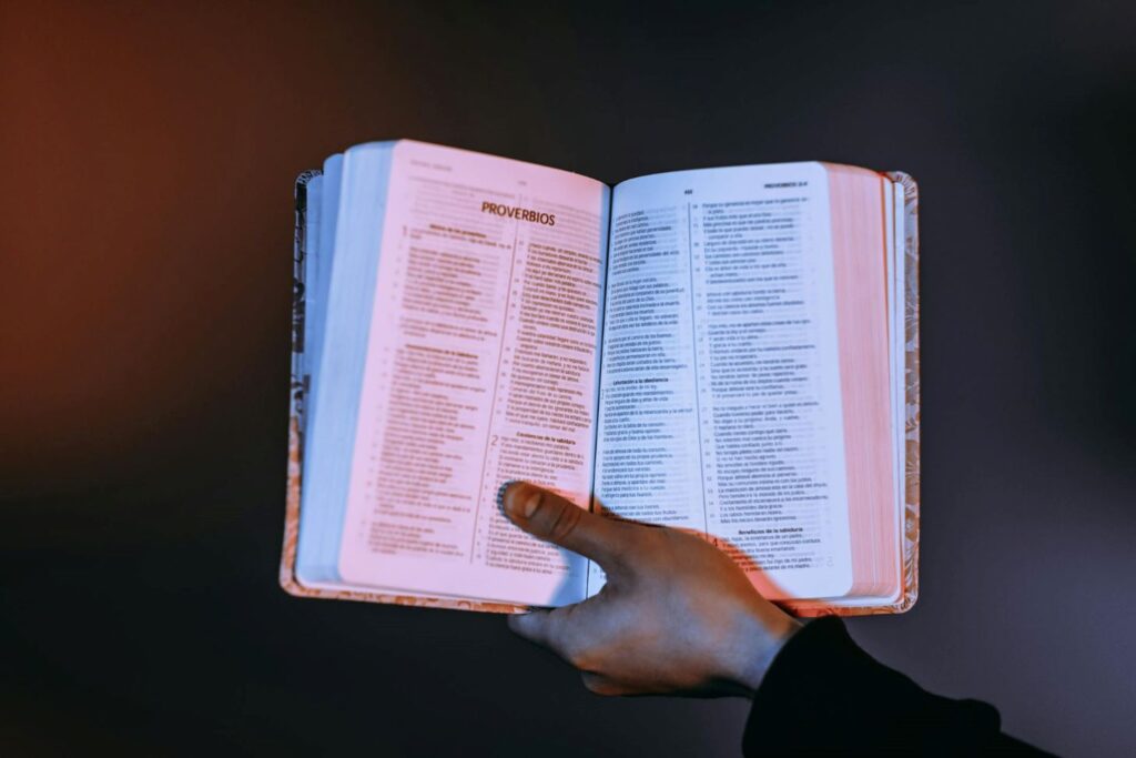 A hand holding an open Bible.