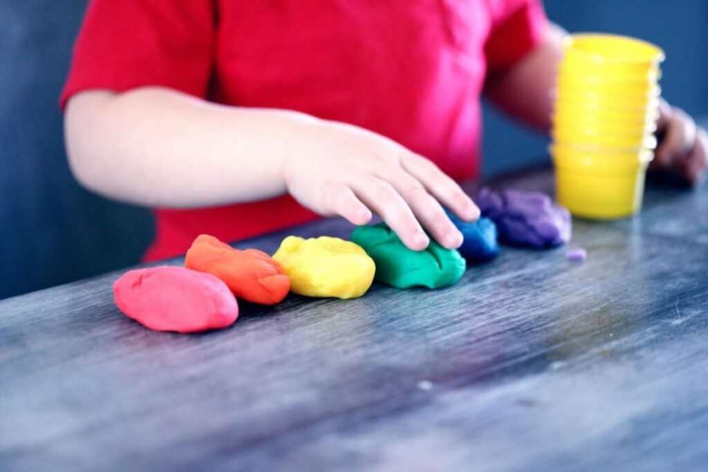 A child sorting colorful clay blobs.