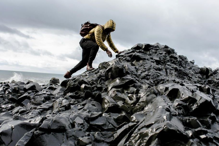 A man climbing across a rocky coast.