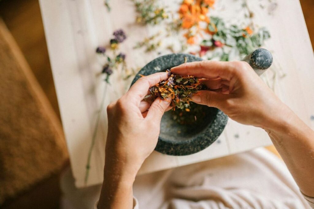 Pounding flower petals into a mortar.