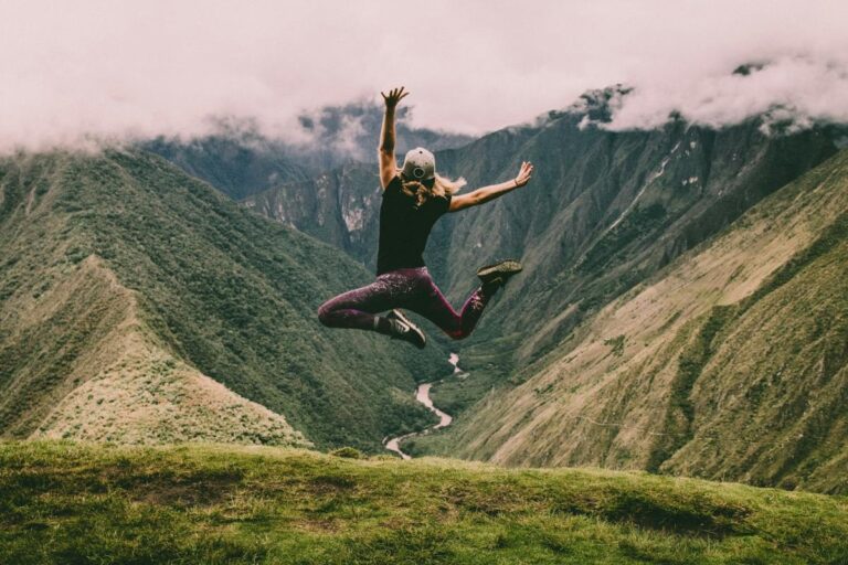 a person jumping in the air on top of the mountain, living life to the fullest