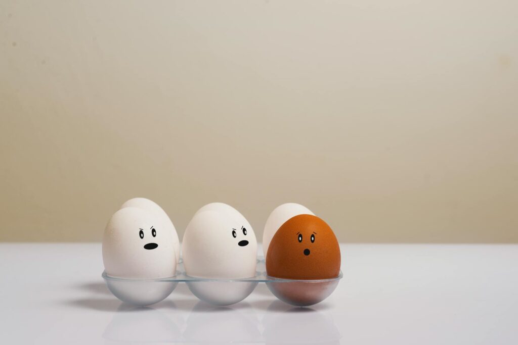 A brown egg surrounded by white eggs.